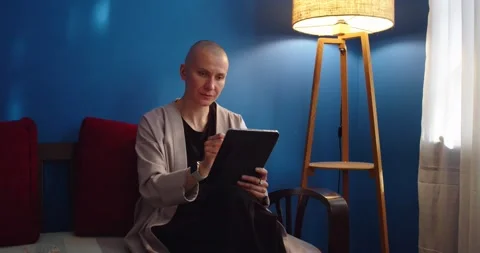 Stylish woman sitting on sofa using ipad and drinking tea at home in evening Stock Footage 200700505