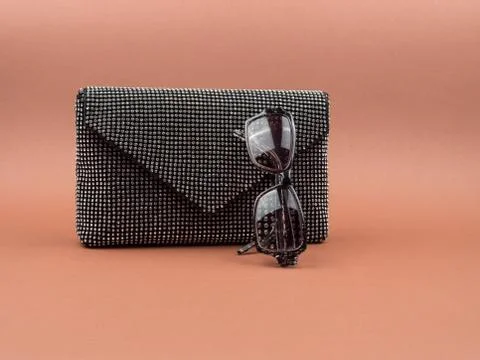 Stylish women's clutch bag, and glasses on a colored background. Stock Photos