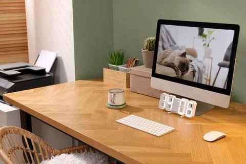 Stylish workplace with computer, cup and cactus near olive wall at home Stock Photos