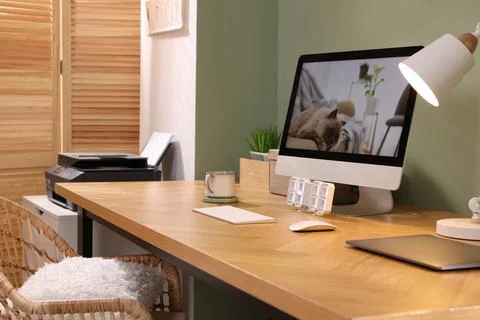 Stylish workplace with computer, laptop and lamp near olive wall at home Stock Photos