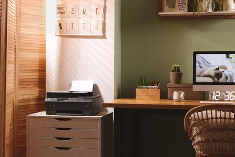 Stylish workplace with computer, printer and houseplant near olive wall at ho Stock Photos
