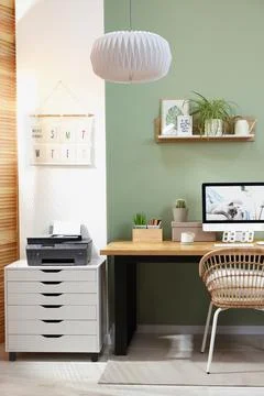 Stylish workplace with computer, printer and houseplant near olive wall at ho Stock Photos