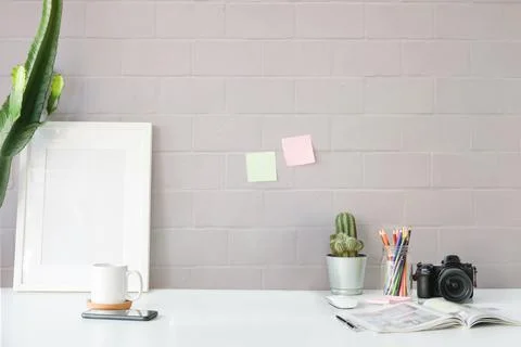 Stylish workplace with empty picture frame, cactus, camera and coffee cup on  Foto stock