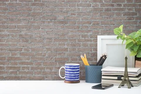 Stylish workplace. Empty picture frame, pencil holder and notebook on white t Stock Photos