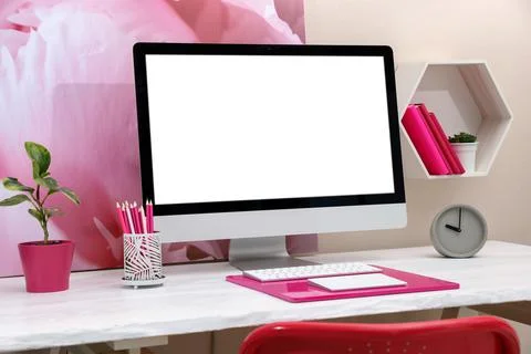 Stylish workplace with modern computer and pink elements indoors. Space for t 库存照片
