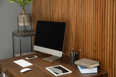 Stylish workplace with modern computer near wooden wall. Space for text Stock Photos