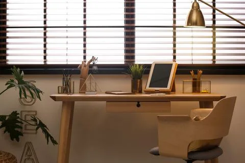 Stylish workplace with modern tablet on table at window. Ideas for interior d Stock Photos