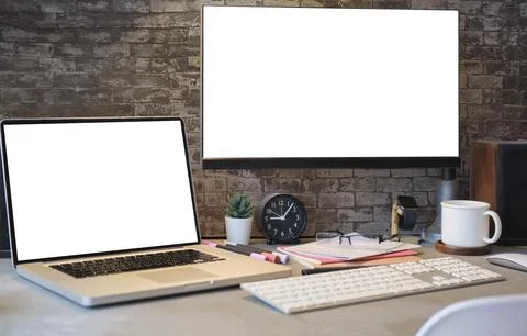 Stylish workplace with white blank computer screen, laptop and supplies. Em.. Stock Photos
