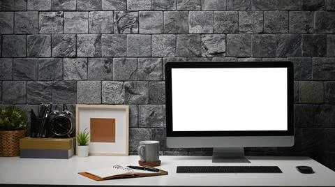 Stylish workspace with computer, picture frame, coffee cup and houseplant on Foto stock
