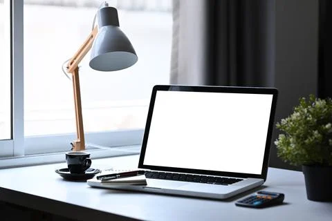 Stylish workspace with laptop computer, lamp, potted plant and coffee cup and on Foto stock