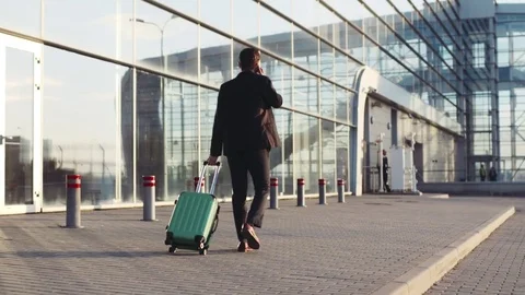 Stylish young bearded man talking on the phone while entering the airport Stock Footage 74886344