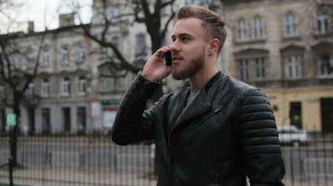Stylish young guy talking on his phone in the street Stock Footage 63469013