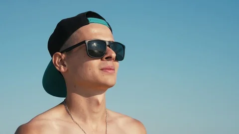 Stylish young man in a cap and sunglasses standing and looking in slo-mo Stock-Footage 120108820