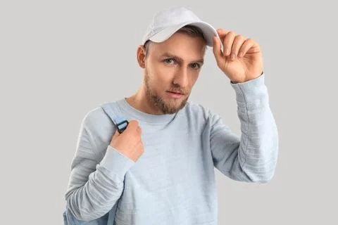 Stylish young man in cap with backpack on light background Stock Photos