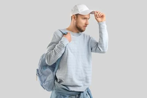 Stylish young man in cap with backpack on light background Stock Photos