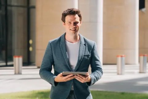 Stylish young man holds a digital tablet against the backdrop of the city bac Stock Photos