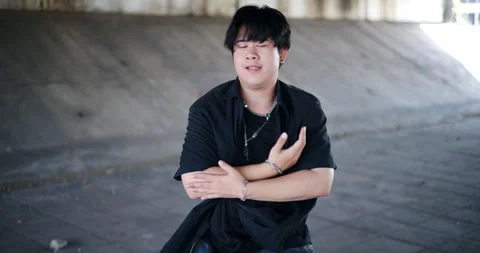A stylish young man performs a freestyle dance under a footbridge in the city. Stockbeeldmateriaal 320920693