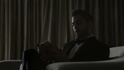 Stylish Young Man Sitting On Sofa With Cellphone In Hands. Man In Suit And White Stock-Footage 153706119