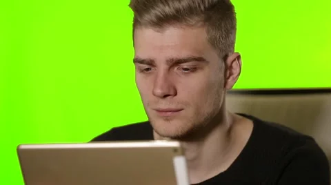 Stylish young man uses tablet with a touch screen on the Chroma-key. Video stock 58280119