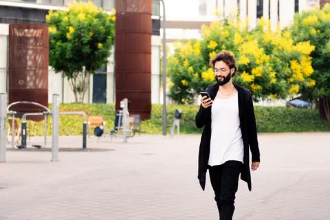 Stylish young man walking using a phone at city Foto stock