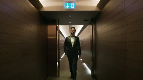Stylish Young Man Walks Down The Hotel Corridor. He Is Dressed In Suit. Man Stock Footage 153714798
