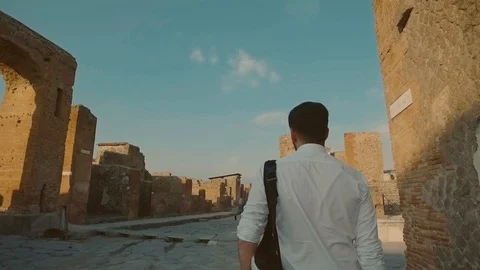 Stylish young well-dressed man with backpack walking in a Roman ruins doing 스톡 동영상 108730399