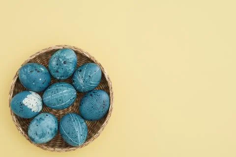 Stylishly colored easter eggs in blue in a basket on a trendy yellow background Stock Photos