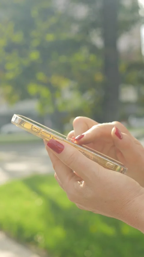 Stylishly Dressed Hands Holding a Smartphone in Bright Natural Light During Stock Footage 285948559