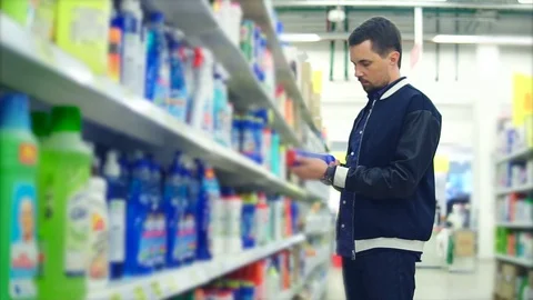 A stylishly dressed man chooses a detergent for the bathroom Stock Footage 76770168