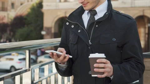 Stylishly dressed man engrossed in typing on his mobile phone Stock Footage 311944606