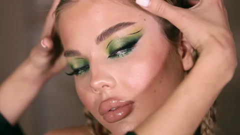 The stylist applying make-up to a young model Stock Footage 229953596