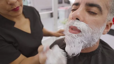 Stylist with client explaining her work during beard dyeing in beauty salon.MOV 스톡 동영상 255797246