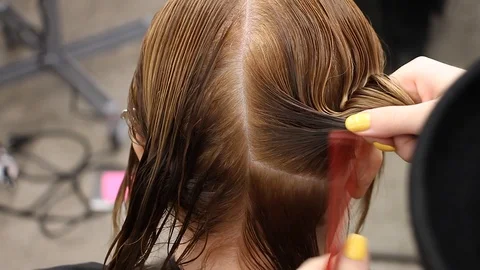 Stylist combs, moisturizes and make hair parting on female head, close-up Stockbeeldmateriaal 113204737