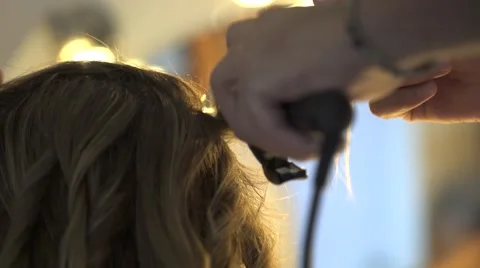Stylist curling hair for young woman Stock Footage