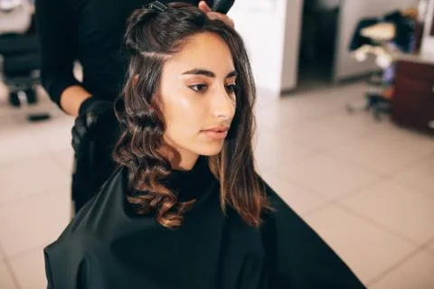 Stylist curling woman's hair in beauty salon Stock Photos