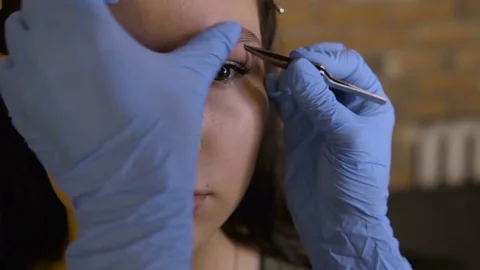 Stylist does beautiful eyebrows to the young beautiful woman. Beauty shop Stock Footage 73941375