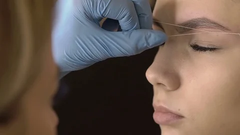 Stylist does beautiful eyebrows to the young beautiful woman. Beauty shop Stock Footage 73945811