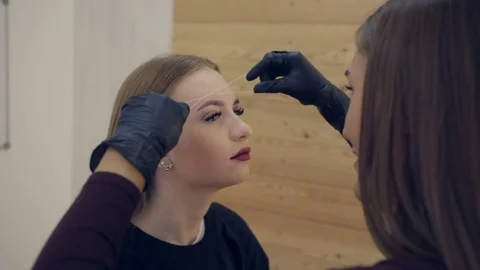 Stylist does beautiful eyebrows to the young beautiful woman. Beauty shop Video stock 81389028