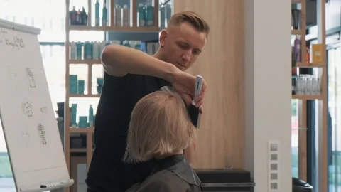 Stylist giving a final touch to a blonde bob haircut in a modern salon Stock Footage 273235191