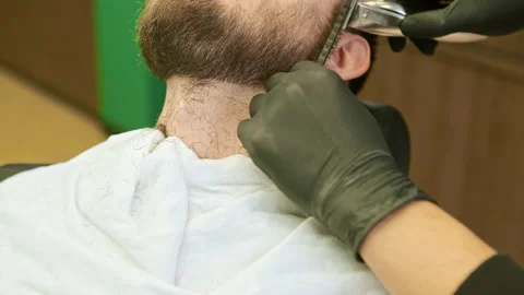 Stylist hands hold plastic comb and trimmer cutting beard Stock Footage 142998498