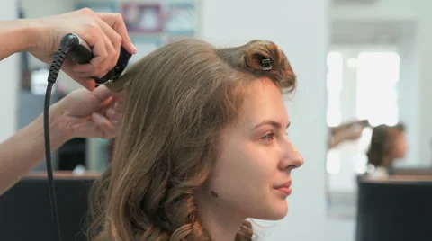 Stylist makes curls brown-haired using a curling Stock Footage 65280221