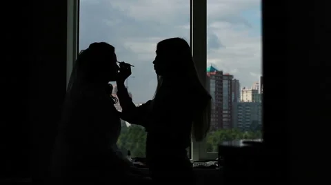 Stylist makes makeup against the window. Silhouettes of people. Stock Footage 65337036