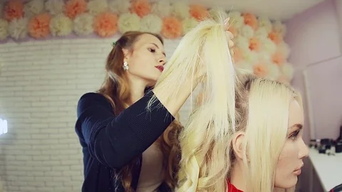 Stylist using curling iron and does curls on blonde girl hair. Stock Footage 71571416