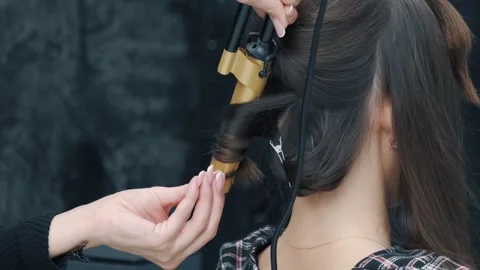 Stylist using a curling iron on client's hair in salon Stock Footage 273221953