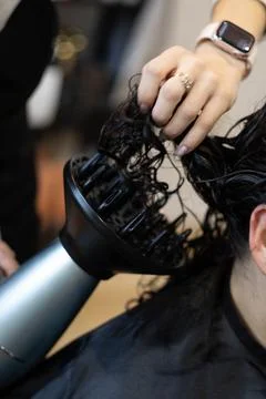 Stylist using a diffuser to enhance curls at a hair salon 스톡 사진