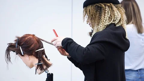 Stylists training at hairdressing workshop, combs hair on dummy head Stockbeeldmateriaal 109900980