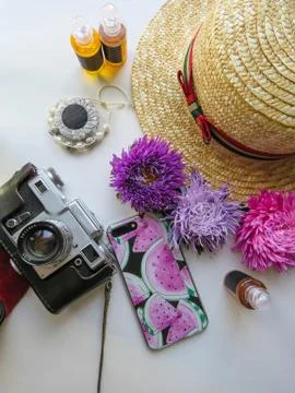 Stylized feminine flatlay with camera, hat, bunch of aster, bracelet and smar Stock Photos