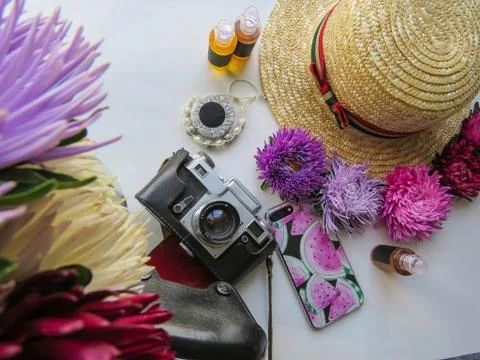Stylized feminine flatlay with camera, hat, bunch of aster, bracelet and smar Stock Photos