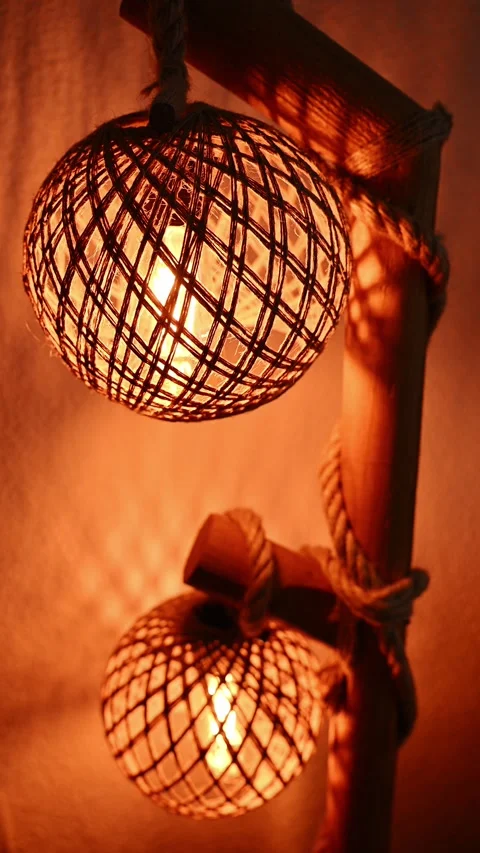 Stylized macrame-style lamps, handcrafted on wooden stands, illuminate room Stock Footage 328157346