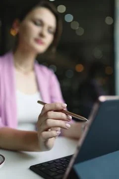 Stylus from a tablet in a woman's hand in front of a tablet on a table in cafe Stock Photos